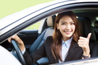 young business woman sitting in car and showing thumbs up
