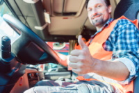 Truck driver man sitting in cabin giving thumbs-up